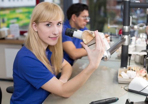 Dental technician producing a prosthesis under a microscope