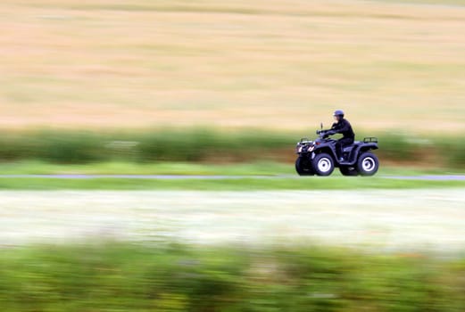 Panning shot of a fast moving black ATV - quad bike