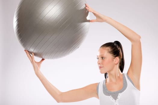 Young woman doing exercises with fitness ball on white background