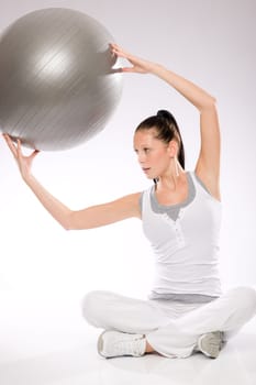 Slim young woman exercising with fitness ball from sitting position
