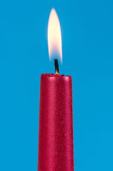 Burning red candle over a blue background