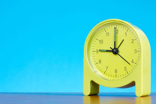 green alarm clock on the table against blue background