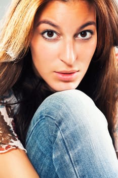 Pretty brunette young woman with chin on knee