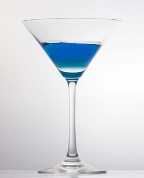 A half filled martini glass over white