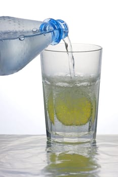 Pouring sparkling water into a caipirinha glass with a lemon slice