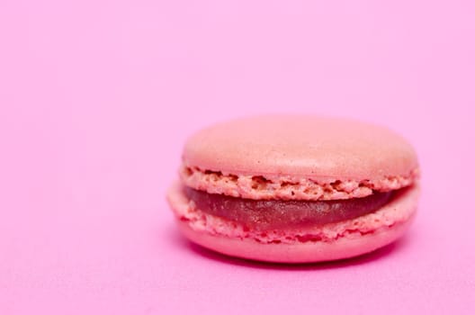 Macaron with strawberry filling on pink background