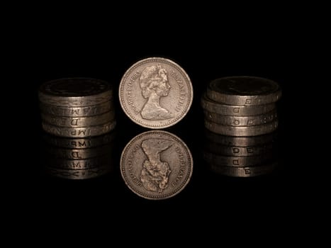 Pound coins reflected on black