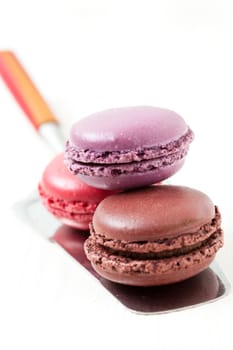 Close-up of three colorful macaroons on cake server on light background