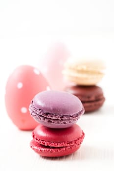 Close-up of colorful macaroons and Easter eggs on light background