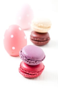 Close-up of colorful macaroons and Easter eggs on light background
