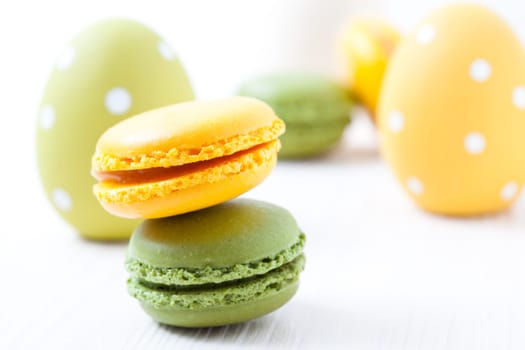 Close-up of colorful macaroons and Easter eggs on light background