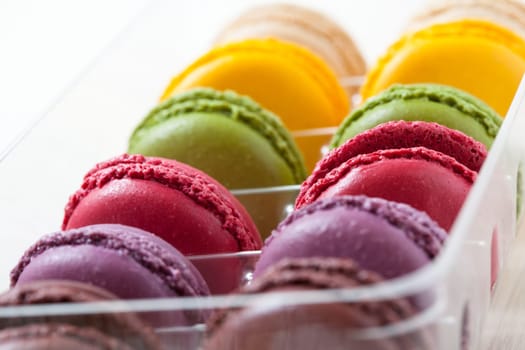 Close-up of assortment of colorful macaroons in tray on light background