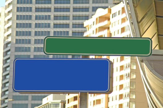 one green and one blue empty street signs, buildings in background