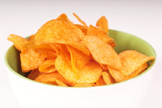 Bowl with potato chips on simple background