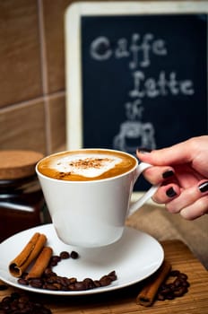 Hand holding cup of delicious coffee