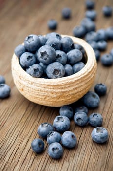 Fresh blueberries in small bowl on wooden surface