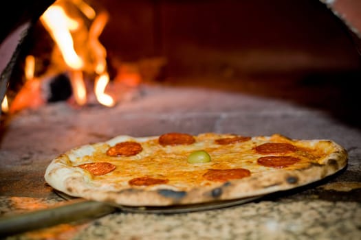 Delicious baked pizza in front of oven