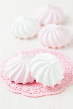 White and pink meringues resting on pink decorative mat on light background