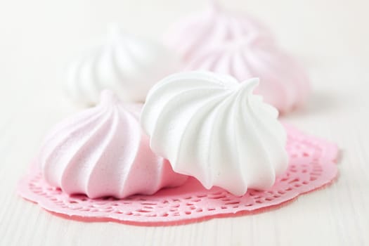 White and pink meringues resting on pink decorative mat on light background