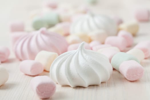 Colorful meringues and marshmallows on light background
