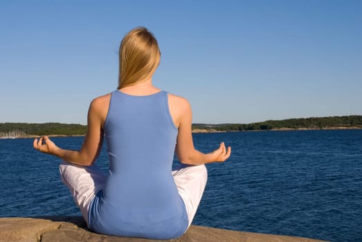 a young woman doing yoga in front of the ocean