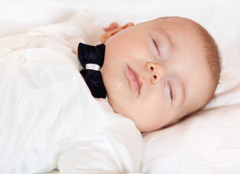 Baby boy dressed for party sleeping peacefully.