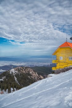 Yellow hut in winter with view towards the valley, Postavaru peak, Romania.