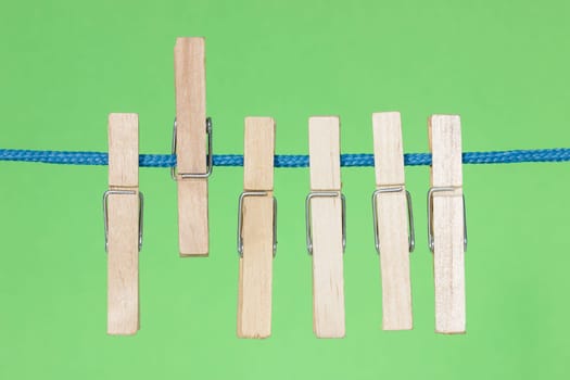 Wooden clothes pegs hang on the green background