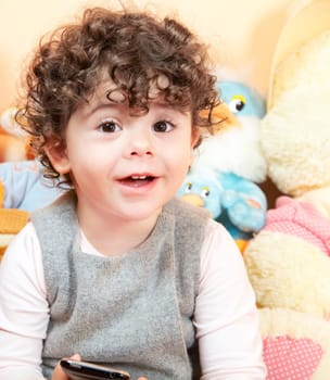 Two year old girl with curly hair portrait, studio shot.