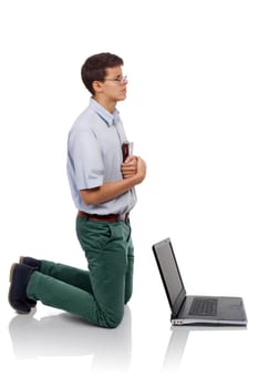 Young man knelt for prayer with the Bible in hand behind a laptop (Concept for  prayer time or for breaking from the worldly things.)