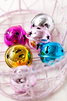 Closeup of colourful Christmas baubles in pink tray on light background