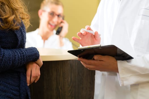Patient and doctor at the reception of a doctor's office,The doctor or dentist holding a clipboard