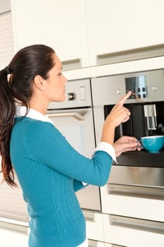 Young woman setting coffee maker machine kitchen cup