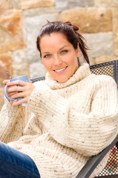 Smiling woman drinking hot cocoa sitting relaxing garden knitted sweater