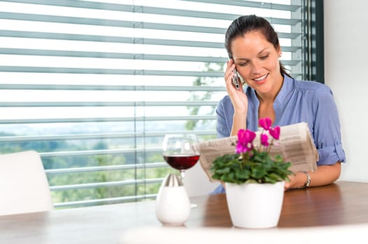 Smiling woman talking mobile phone relaxing reading home living room