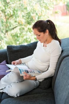 Young woman reading magazine living room couch sofa