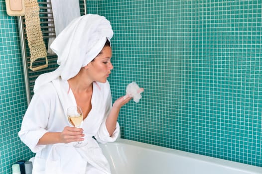 Young woman relaxing bathroom foam bathtub wine wrapped towel