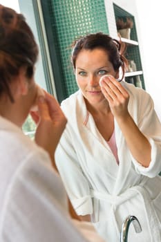 Young woman cleaning face cotton pads bathrobe bathroom morning preparation