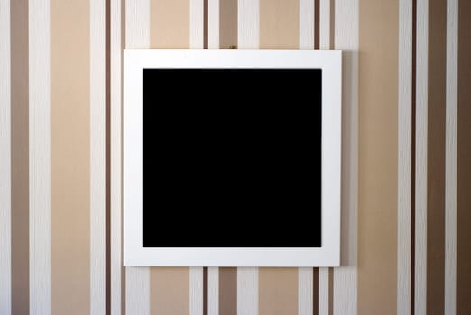 The close-up of a picture frame in front of a strikingly striped wallpaper.