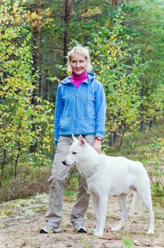 The woman with a dog walk in an autumn wood