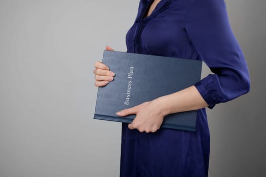 Woman holding business plan. Gray background.