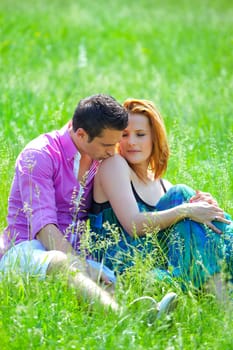 Young man kissing his girlfriend's shoulder outdoor in summer.