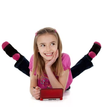 Cute female child lying on floor playing electronic game on white background
