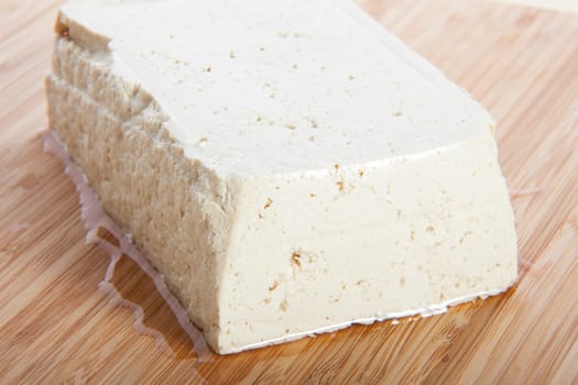 Block of fresh tofu on cutting block.