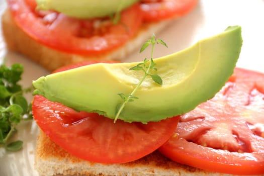 Delicious fresh slice of avocado with tomato and thyme on toast.
