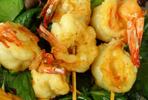 Yummy fried shrimp skewers on a bed of lettuce ready to serve.