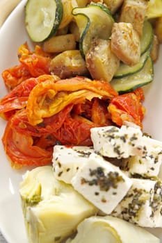 Delicious tray of rustic vegetables including artichokes, sundried tomatoes, aubergine, zucchinis and feta cheese.