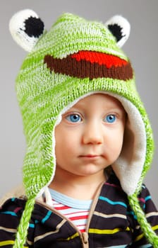 Portrait of a cute little adorable child with funny green hat over gray background