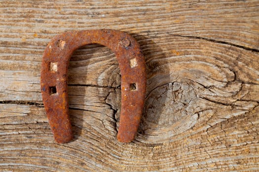 Antique horseshoe luck symbol rusted on vintage wood background