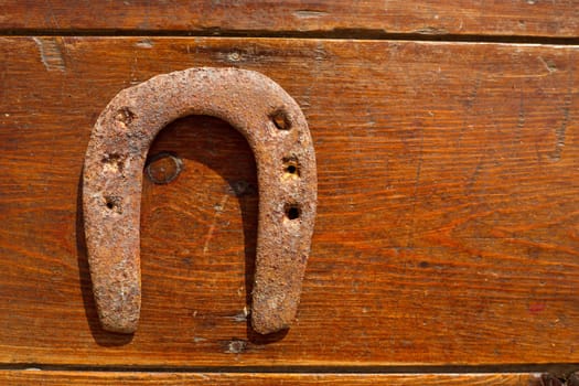 Antique horseshoe luck symbol rusted on vintage wood background